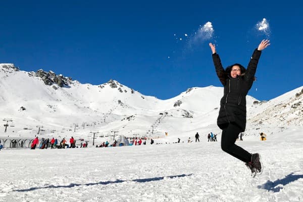 Queenstown Skiiing Girl in black ski gear jumping at Queenstown ski field