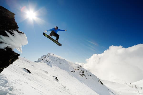 Snowboarding Queenstown, New Zealand Person snowboard jumping on ski slopes New Zealand