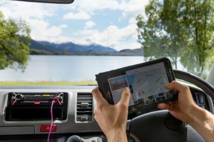 Camping in New Zealand Person looking at tablet in campervan