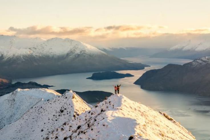 Two friends standing on top of a snowy mountain Two friends standing on top of a snowy mountain